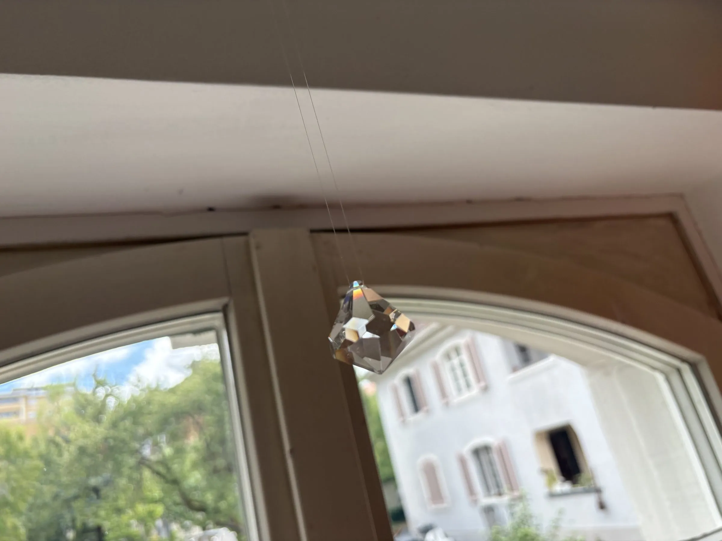 Ein Kristall hängt im Rundbogenfenster der Praxis